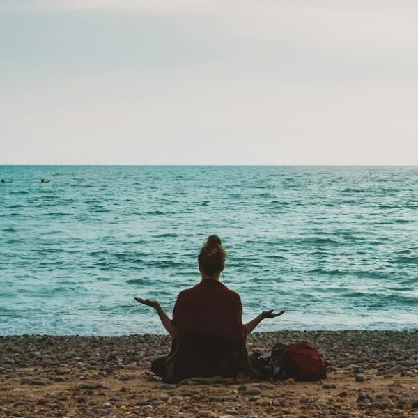 A person walking calmly by the sea as part of a steady wellness routine