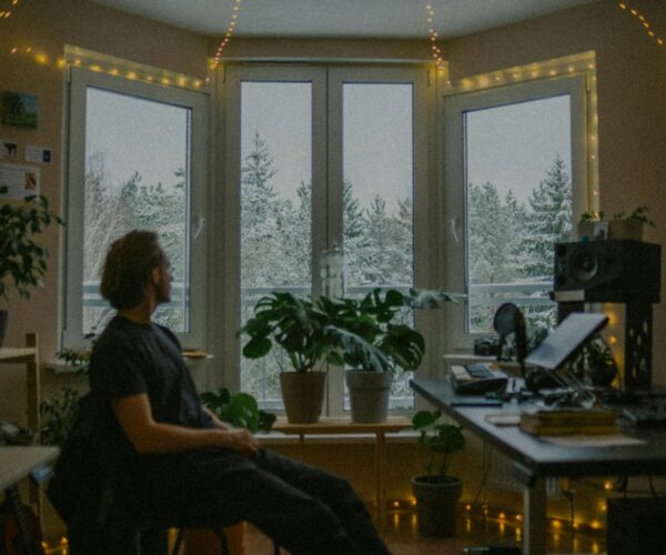 A person pausing in a calm room and looking through a window