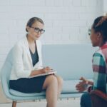 A mental health professional listening and taking notes during an evaluation